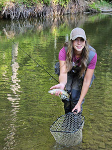 Fishing in river holding brown trout fish.